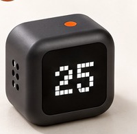A black cube timer with a white dot-matrix display reading 25 and an orange button on top.